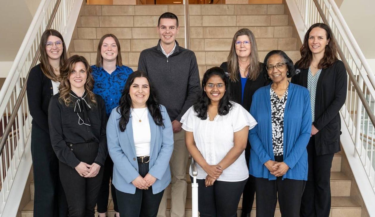 Group photo of CHP Student Services Office standing on a staircase in the Center for Health Sciences building